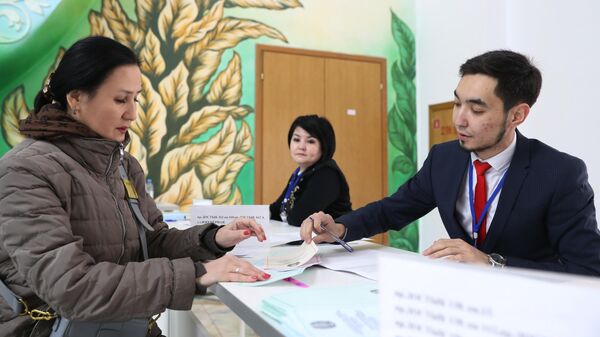 Женщина получает бюллетень на избирательном участке в Алма-Ате на внеочередных парламентских выборах в Казахстане