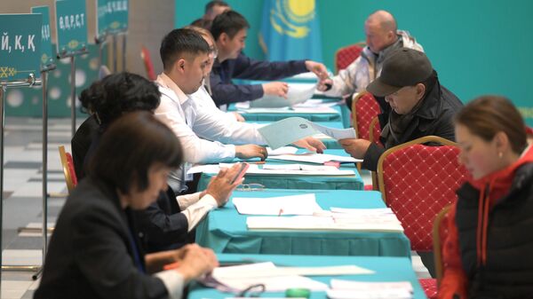 Люди получают бюллетени на избирательном участке на внеочередных парламентских выборах в Казахстане