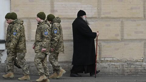 Украинские военнослужащие проходят мимо монаха в Киево-Печерской лавре, 14 марта 2023 года 