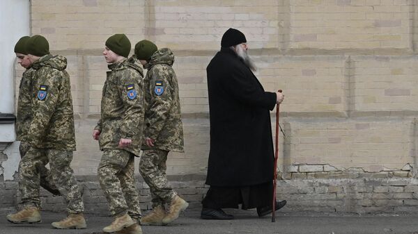Украинские военнослужащие проходят мимо монаха в Киево-Печерской Лавре