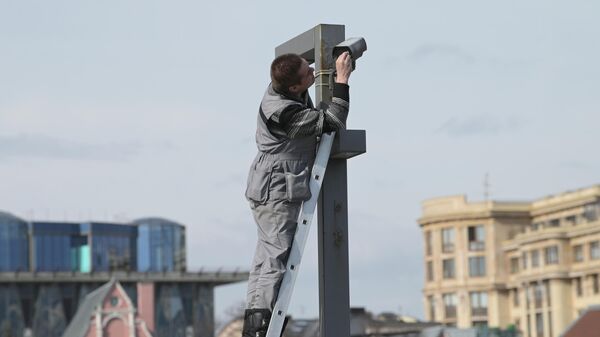 Рабочий протирает камеру видеонаблюдения в центре Москвы