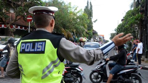 Полицейский регулирует движение на дороге на Бали, Индонезия 