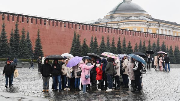 Люди с зонтами во время дождя на Красной площади в Москве