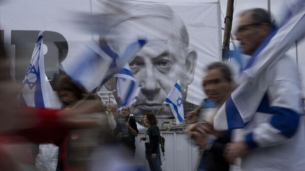 Демонстранты рядом с баннером с изображением премьер-министра Израиля Биньямина Нетаньяху