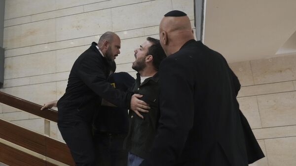 Сотрудники службы безопасности задеживают протестующего, ворвавшегося в здание парламента в Иерусалиме. 27 марта 2023