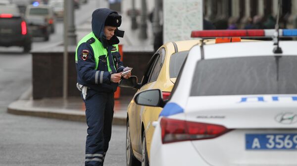 Сотрудник ГИБДД проверяет документы у водителя в Москве