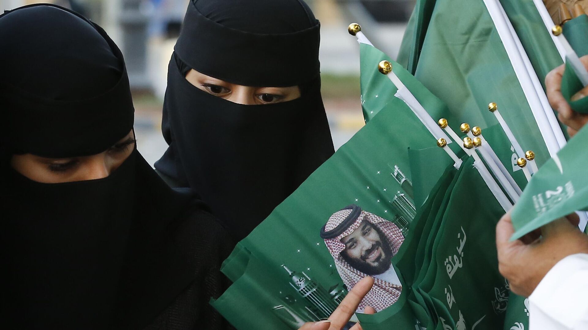 Женщины разглядывают флаги с изображением наследного принца Саудовской Аравии - РИА Новости, 1920, 20.10.2023