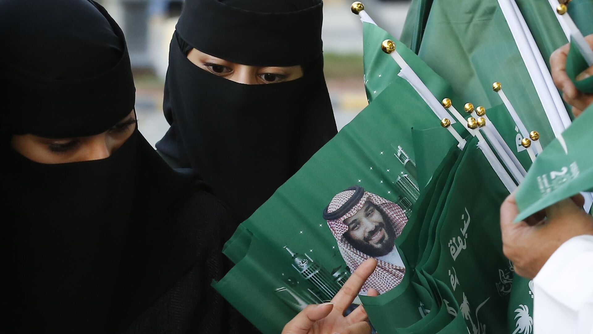 Женщины разглядывают флаги с изображением наследного принца Саудовской Аравии - РИА Новости, 1920, 20.10.2023