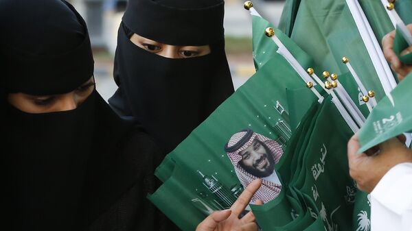 Женщины разглядывают флаги с изображением наследного принца Саудовской Аравии