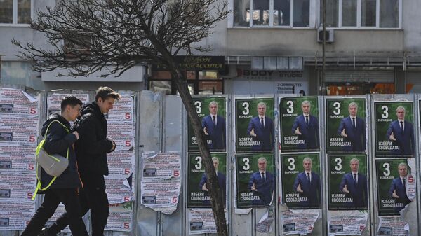 Люди проходят мимо предвыборных плакатов в Софии накануне парламентских выборов