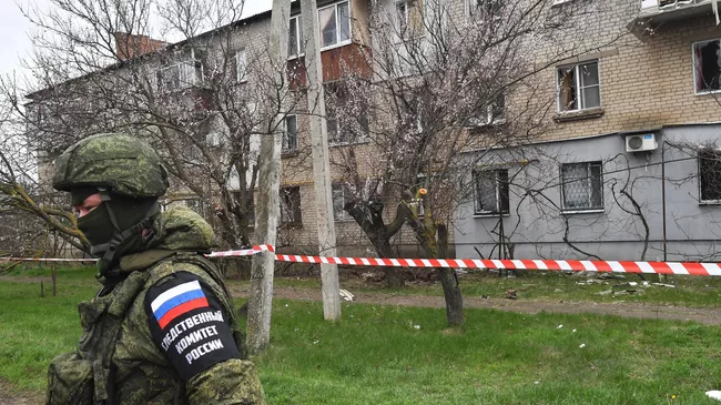 Сотрудник Следственного  комитета России у жилого многоквартирного дома в Мелитополе, поврежденного в результате обстрела со стороны ВСУ
