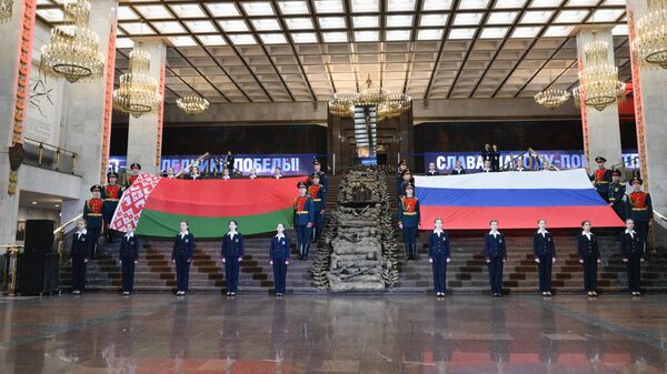 Волонтеры и военнослужащие развернули национальные флаги государств в рамках акции, посвященной Дню единения народов Беларуси и России, в Москве