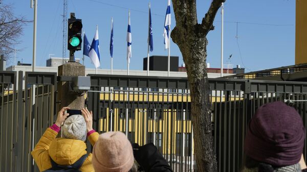 Люди фотографируют флаги НАТО и Финляндии над зданием Министерства иностранных дел в Хельсинки