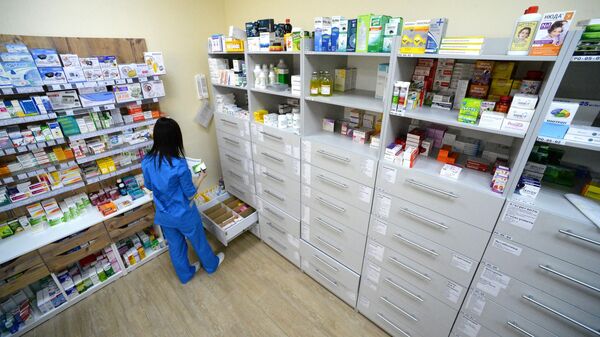 Фармацевт возле стеллажа с лекарствами в аптеке