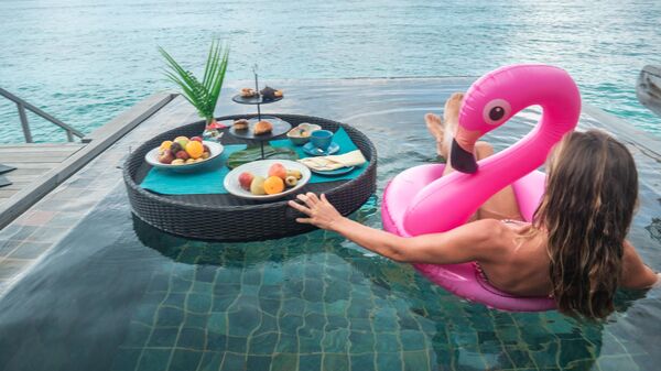 Девушка завтракает в бассейне отеля на Мальдивах 