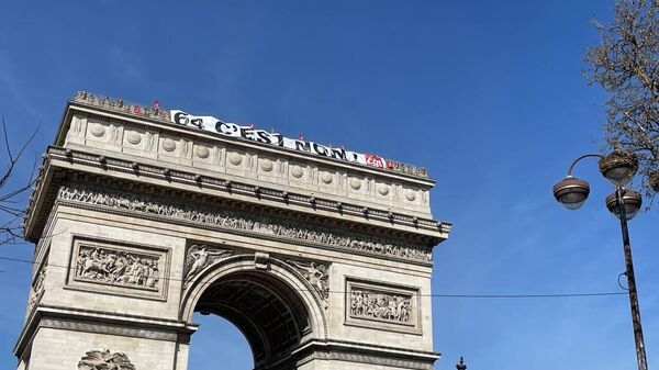 Баннер с эмблемой профсоюзов и против повышения пенсионного возраста до 64 лет на Триумфальной арке в Париже