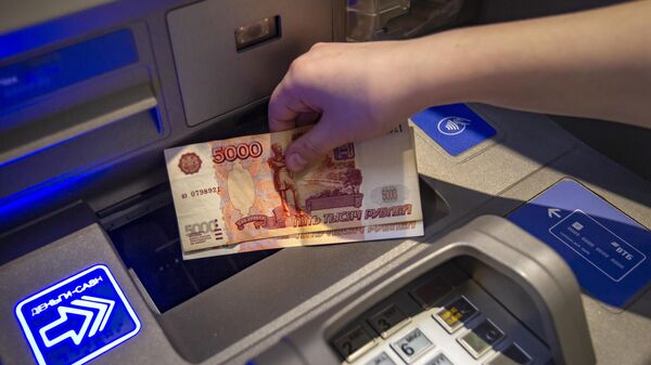 Посетитель кладет деньги на банковский счет в банкомате