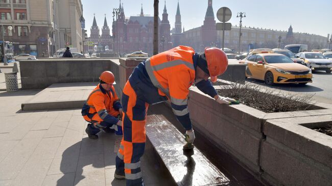 Сотрудники коммунальной службы красят лавочки на Тверской улице в Москве