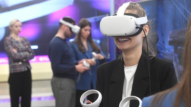 Посетительница в очках виртуальной реальности на VR-стенде РИА Новости