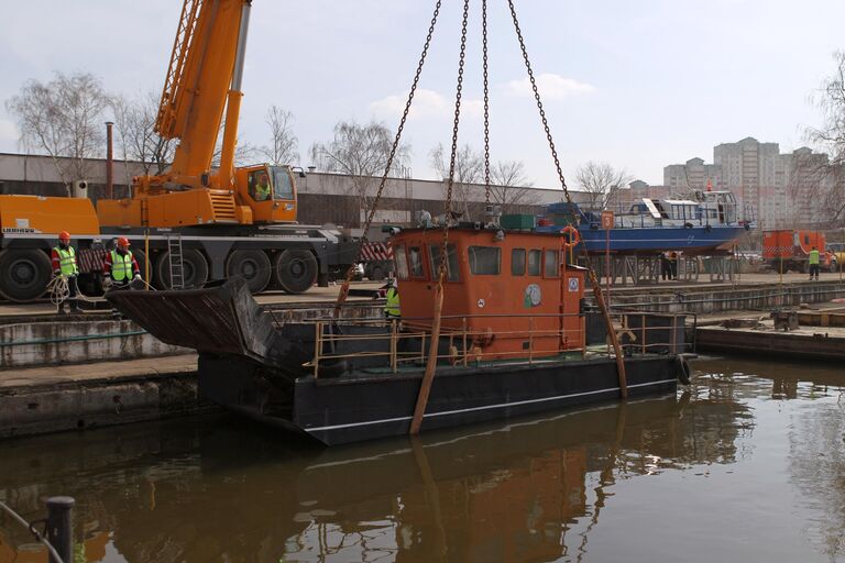 Сотрудники ГУП Мосводосток спускают на воду мусоросборное судно во время подготовки к открытию технической навигации на Москве-реке