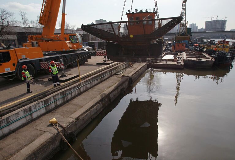 Сотрудники ГУП Мосводосток спускают на воду мусоросборное судно во время подготовки к открытию технической навигации на Москве-реке