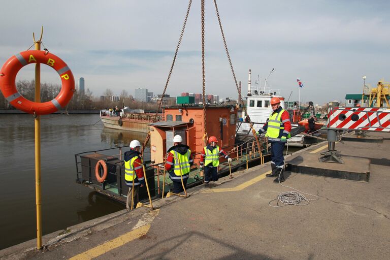 Сотрудники ГУП Мосводосток возле мусоросборного судна, спущенного на воду во время подготовки к открытию технической навигации на Москве-реке