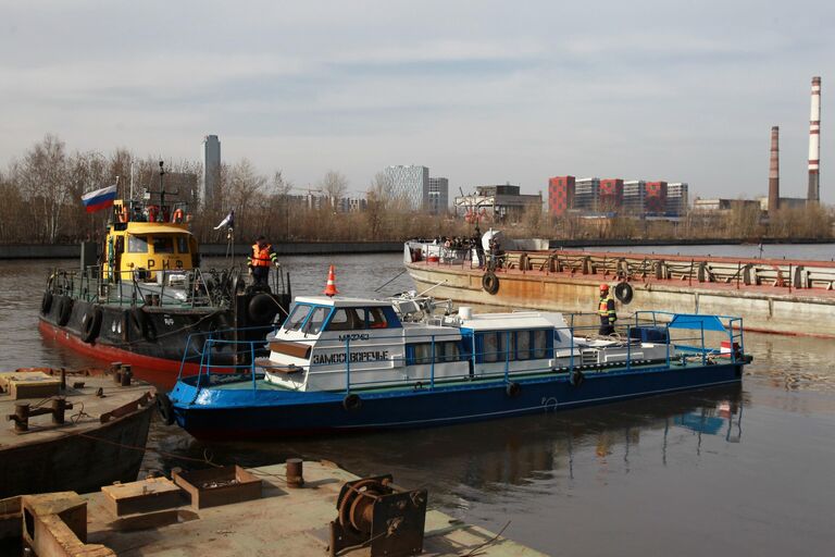 Сотрудники ГУП Мосводосток буксируют грузовой катер Яуза-1 во время подготовки к открытию технической навигации на Москве-реке