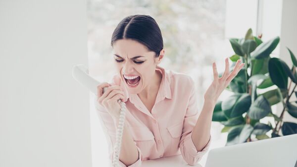 Девушка кричит в телефонную трубку в офисе