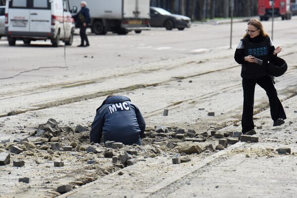 Сотрудник МЧС обследует воронку от взрыва рядом с рынком, подвергшемся обстрелу со стороны ВСУ, в Ворошиловском районе Донецка