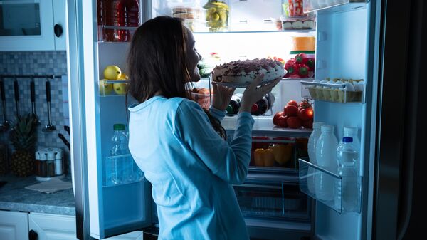 Женщина достает торт из холодильника
