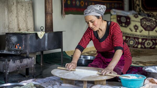 Женщина раскатывает тесто в деревне в горах Азербайджана