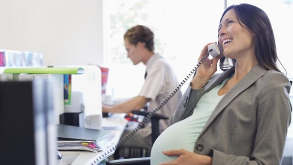 Беременная женщина во время работы в офисе
