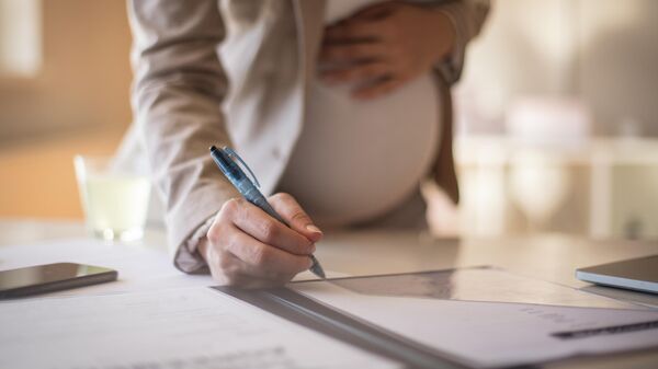 Беременная девушка подписывает документы 