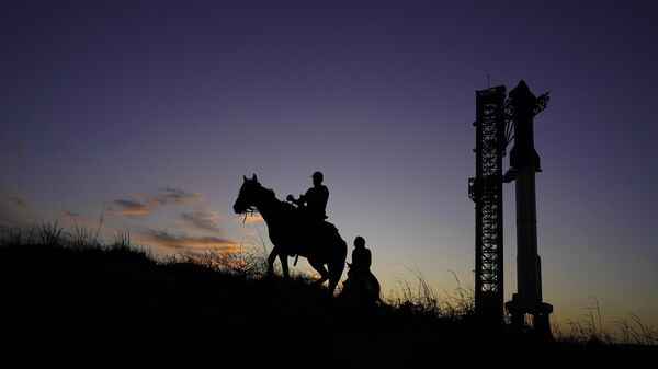 Мужчины едут на лошадях мимо космического корабля SpaceX Starship  в Бока-Чика, штат Техас