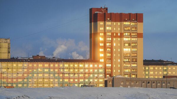 Закатное солнце отражается в окнах жилого дома в городе Норильск