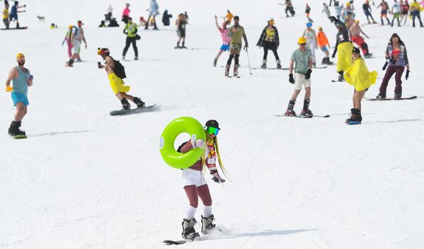 Участники Совершенно летнего спуска в летней одежде на горнолыжной трассе горы Зеленая на фестивале GrelkaFest в поселке Шерегеш Кемеровской области