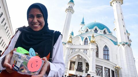 Верующая раздает сувениры в день праздника Ураза-байрам у мечети Кул Шариф