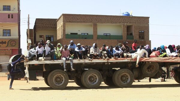 Люди спасаются от уличных боев между силами двух соперничающих суданских генералов в кузове грузовика