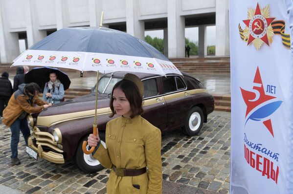 Девушка в исторической военной форме во время старта ретроралли Автопробег Победы у Музея Победы в Москве. На втором плане – автомобиль ГАЗ-М-20 Победа