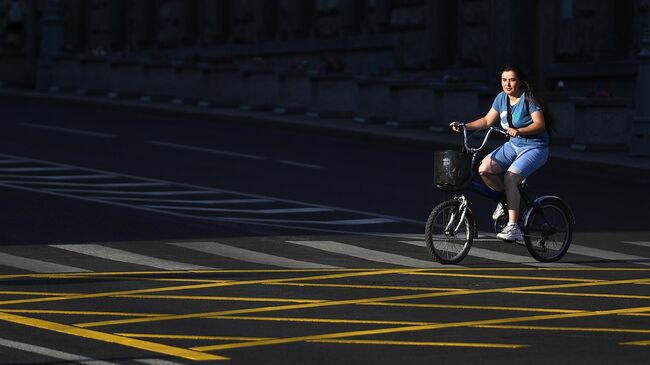 Женщина на велосипеде едет по пешеходному переходу