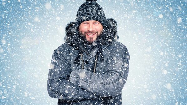 Улыбающийся мужчина стоит под снегопадом