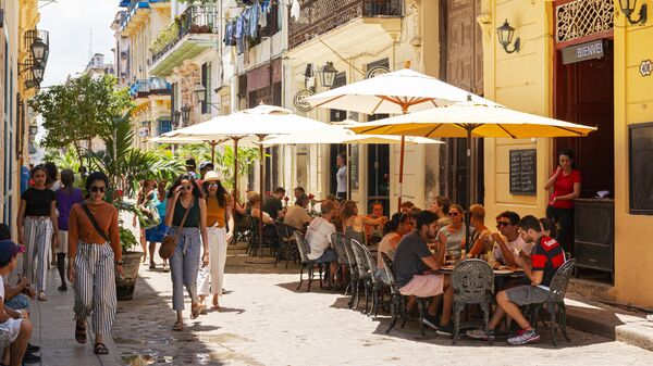 Люди проходят мимо кафе на улице Гаваны