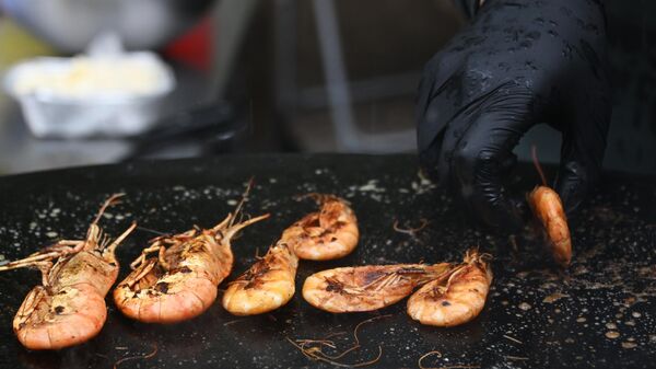 Мужчина готовит креветки на фестивале фудтраков в парке Сокольники в Москве