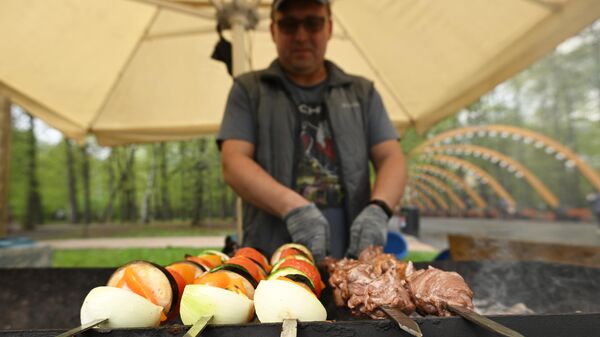 Мужчина готовит шашлык на фестивале фудтраков в парке Сокольники в Москве