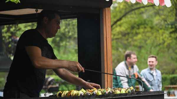 Мужчина готовит овощи на гриле на фестивале фудтраков в парке Сокольники в Москве
