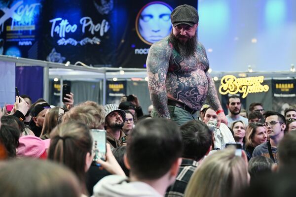 Участник демонстрирует татуировку зрителям на ХХ Московском фестивале татуировки в Amber Plaza Hall в Москве