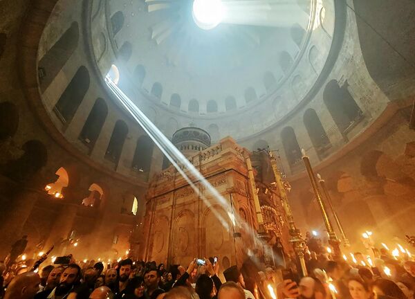Верующие со свечами и лампадами, зажженными от Благодатного огня, в Кафедральном соборе Воскресения Христова в Иерусалиме