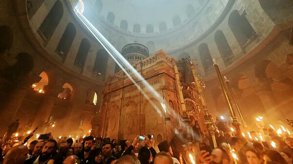 Верующие со свечами и лампадами, зажженными от Благодатного огня, в Кафедральном соборе Воскресения Христова в Иерусалиме