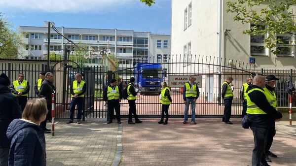 Представители мэрии в сопровождении полиции стоят возле ворот школы при российском посольстве в Варшаве