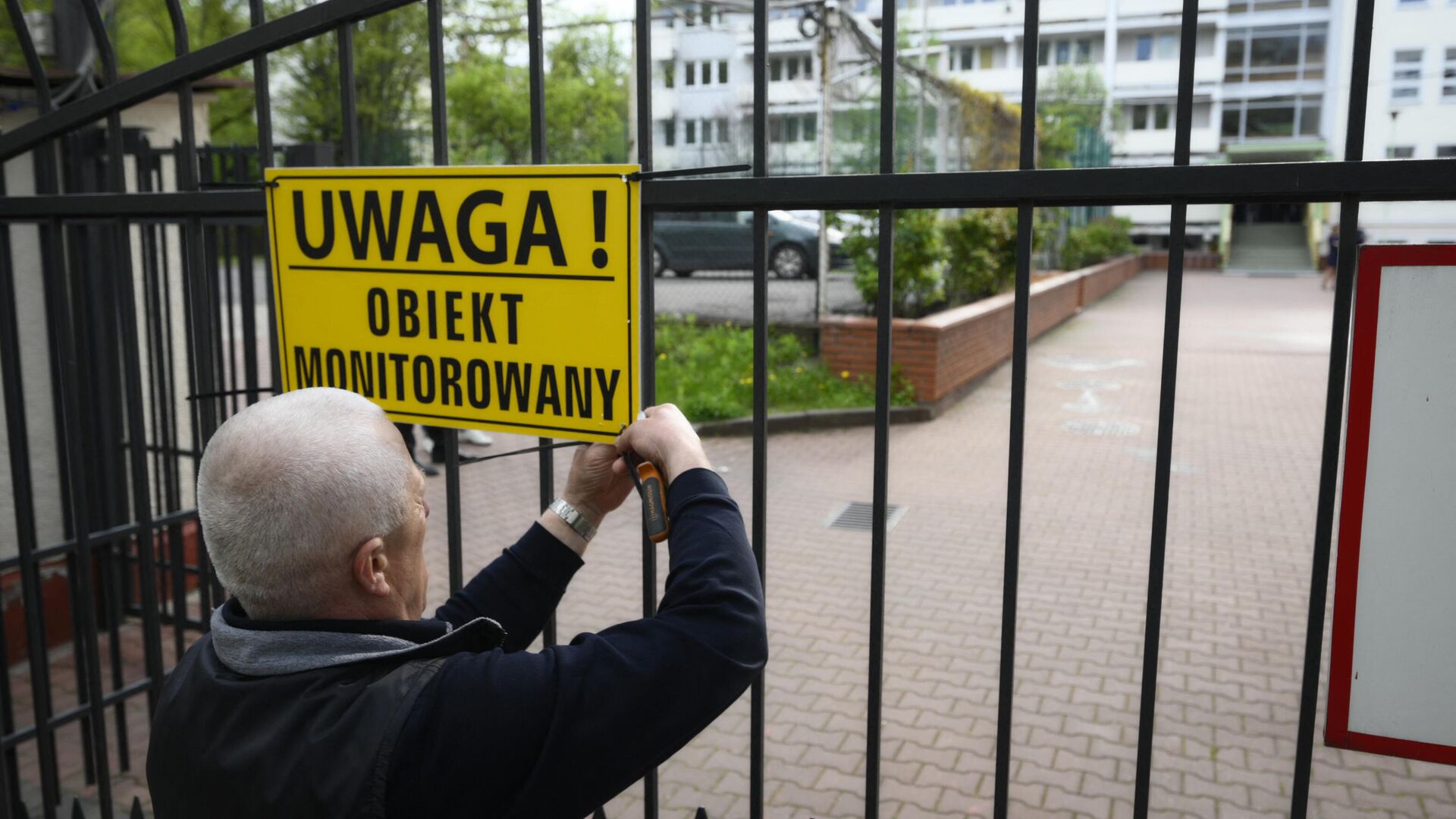 Представитель мэрии вешает предупреждающий знак на ворота школы при российском посольстве в Варшаве - РИА Новости, 1920, 30.04.2023